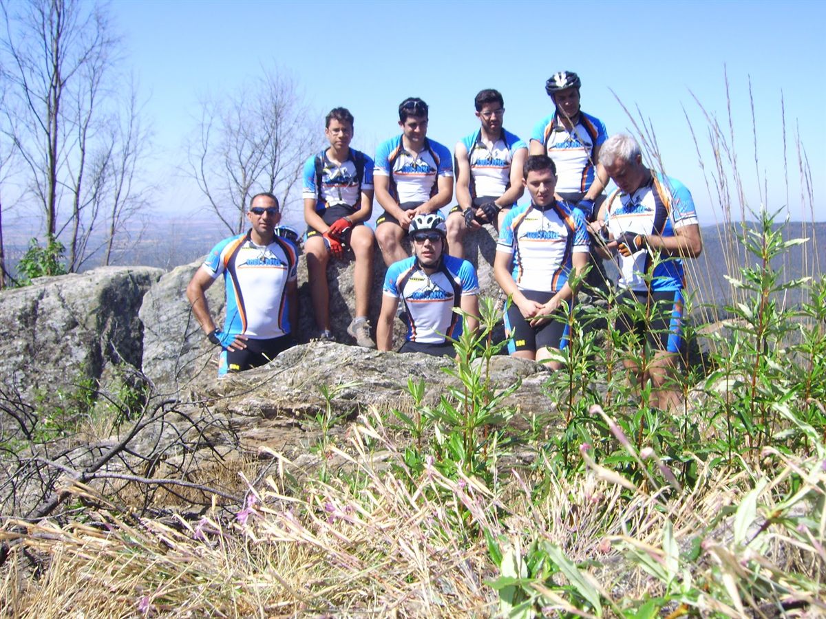 Nove elementos do grupo sentados nas rochas da Serra d'Ossa com o primeiro equipamento, em azul, branco e laranja
